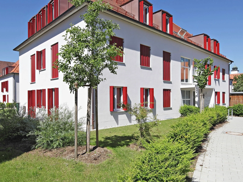 Rote Fensterläden an einem weißen Haus mit rotem Dach